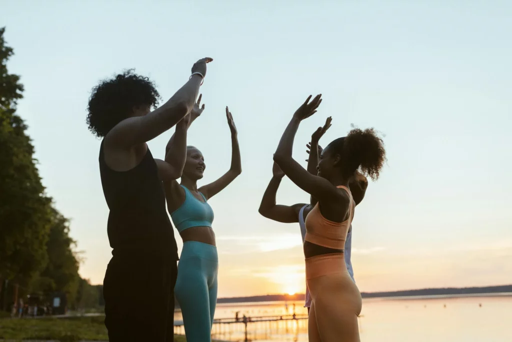 Mujeres alzando los brazos haciendo ejercicio en una playa